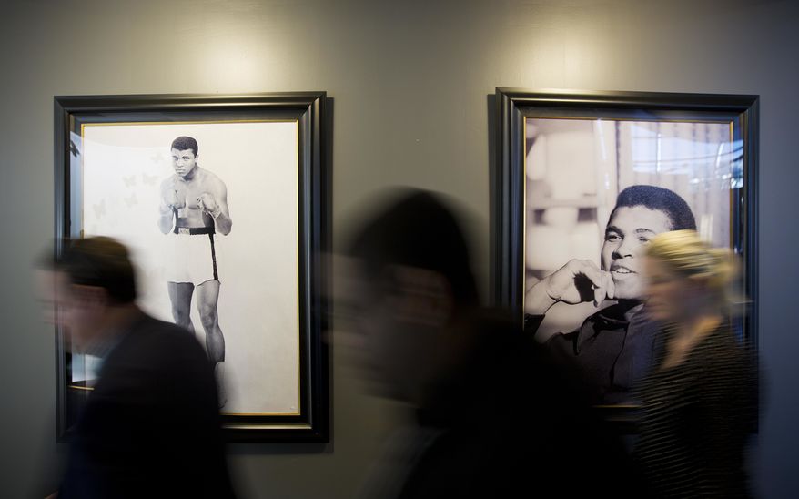 Photos of Muhammad Ali hang on the wall as people pass by before the start of a press conference regarding the funeral for Ali at the Muhammad Ali Center, Monday, June 6, 2016, in Louisville, Ky. The president of Turkey and king of Jordan joined the long line of world leaders, religious figures and superstars set to speak at Ali's funeral Friday. (AP Photo/David Goldman)