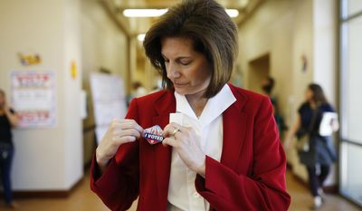 In this May 31, 2016, photo, U.S. Senate candidate Catherine Cortez Masto applies a sticker to her jacket after voting at an early voting site in Las Vegas. A former state attorney general, Masto, would be the first Latina ever to serve in the U.S. Senate. (AP Photo/John Locher)