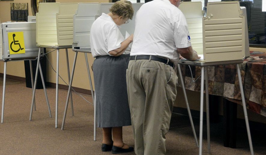A couple fills out primary election ballots, Tuesday, June 7, 2016, at the Church at the Gate polling place in Sioux Falls, S.D. Poll workers say turnout was light Tuesday morning. (AP Photo/Dirk Lammers)
