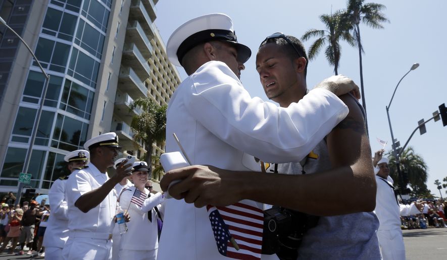 Navy Senior Chief Dwayne Beebe, center, embraces Jonathan Franqui, right, after proposing to him during the gay pride parade Saturday, July 21, 2012, in San Diego. For the first time ever, U.S. service members marched in a gay pride event decked out in uniform Saturday, after a recent memorandum from the Defense Department to all military branches made an allowance for the San Diego parade - even though its policy generally bars troops from marching in uniform in parades. (AP Photo/Gregory Bull)