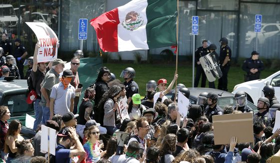 An anti-Donald Trump protester waves a Mexican flag outside the California Republican Party 2016 Convention on April 29 in Burlingame, Calif. (Associated Press)