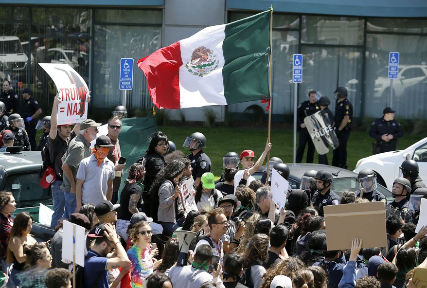 An anti-Donald Trump protester waves a Mexican flag outside the California Republican Party 2016 Convention on April 29 in Burlingame, Calif. (Associated Press)