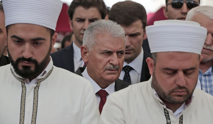 Flanked by imams offering prayers, Turkey&#x27;s Prime Minister Binali Yildirim attends the funeral procession for two of the victims killed in Tuesday&#x27;s explosion, at Fatih mosque in Istanbul, Wednesday, June 8, 2016. The bomb attack, targeting a bus carrying riot police during rush hour traffic in Istanbul, has killed a number of people and wounded dozens of others. It marks the fourth bombing to hit the Turkish city this year and there was no immediate responsibility claim but Turkey has witnessed an increase in violence linked to Kurdish rebels and Islamic State militants. (AP Photo/Lefteris Pitarakis)