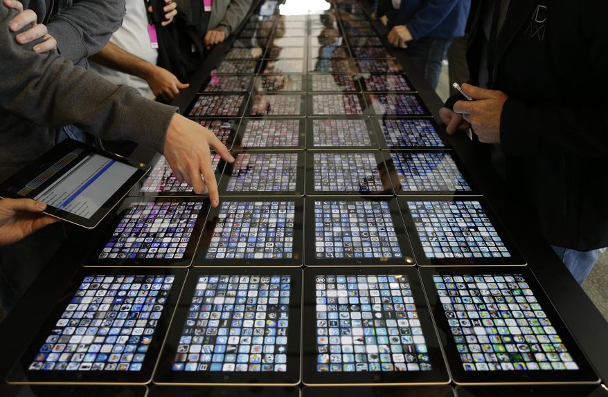 FILE - In this Monday, June 10, 2013, file photo, developers look over new apps being displayed on iPads at the Apple Worldwide Developers Conference in San Francisco. Apple says it will start showing paid ads when people search for apps in its popular mobile store. The ads are among several changes that Apple hopes will bring in more money for itself and independent software developers who want to promote apps for the iPhone or iPad. (AP Photo/Eric Risberg, File)