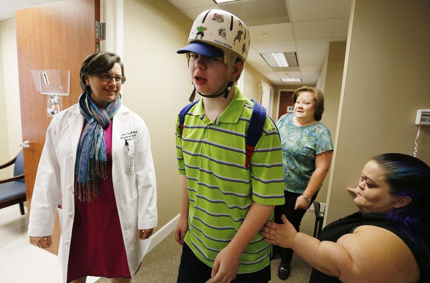 In this Wednesday, May 11, 2016 photo, Dr. Gretchen Von Allmen, left, a pediatric neurologist, at Memorial Hermann and a University of Texas Health Science Center Houston professor studying epilepsy visits with patient Travis Johnson, center, his mother Cindy Johnson Kercheval, second from right, and his sister Laura Kercheval, in Houston. Travis was diagnosed with a genetic form of epilepsy at 18 months and has undergone numerous medical procedures including brain surgery to help control his seizures. In July 2015 his mother considered trying cannabidiol or CBD oil, derived from the hemp plant, to further help her son gain some control of his seizures. CBD oil is currently undergoing drug trials and therefore is not a prescribed method in the treatment of epilepsy. Allmen hopes she can prescribe CBD to her patients in the near future. (Kin Man Hui/The San Antonio Express-News via AP) RUMBO DE SAN ANTONIO OUT; NO SALES; MANDATORY CREDIT