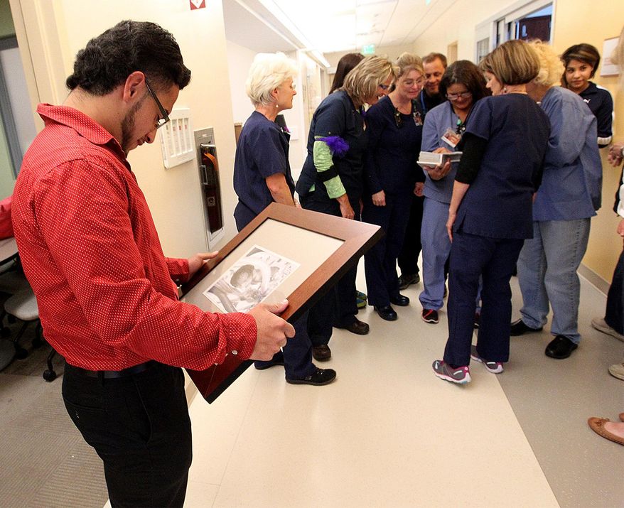 Rosalio Garcia looks at a picture of himself which hangs on a wall in the Neonatal Intensive Care Unit at St. Mary's Hospital in Grand Junction, Colorado, during a visit to the unit on April 25, 2016. Meanwhile, some of the nurses who took care of him 18 years ago look at a photo album he brought with him. (Dean Humphrey/The Grand Junction Daily Sentinel via AP) ** FILE **