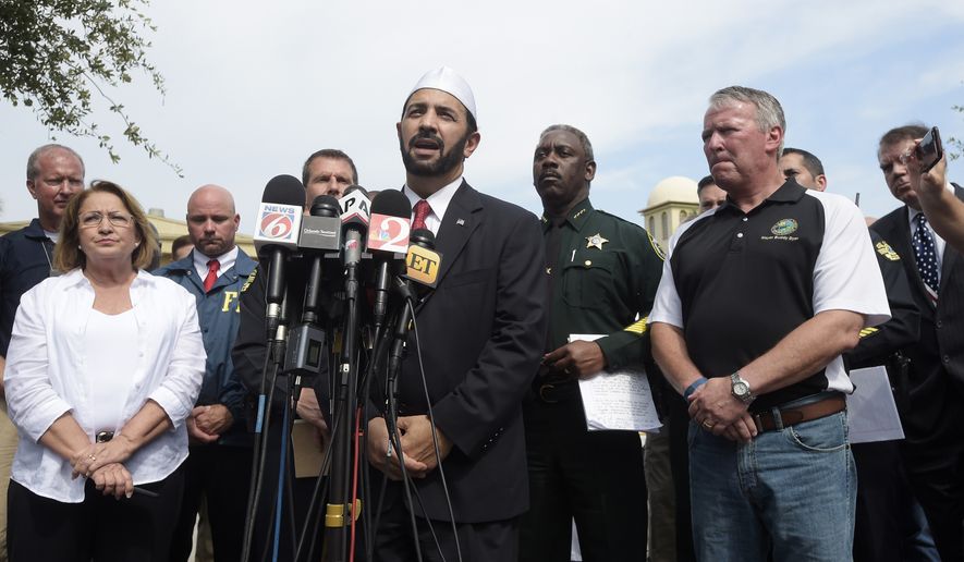 Imam Muhammad Musri, center, president of the Islamic Society of Central Florida, addresses reporters while flanked by members of law enforcement and community leaders during a news conference after a shooting involving multiple fatalities at a nightclub in Orlando, Fla., Sunday, June 12, 2016. (AP Photo/Phelan M. Ebenhack)