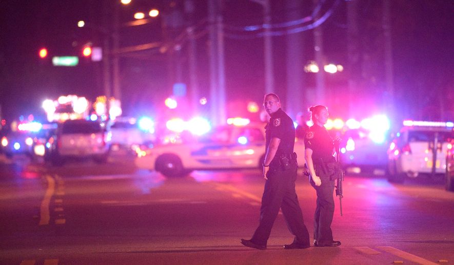 Police officers stand guard down the street from the scene of a shooting involving multiple fatalities at a nightclub in Orlando, Fla., Sunday, June 12, 2016. (AP Photo/Phelan M. Ebenhack)