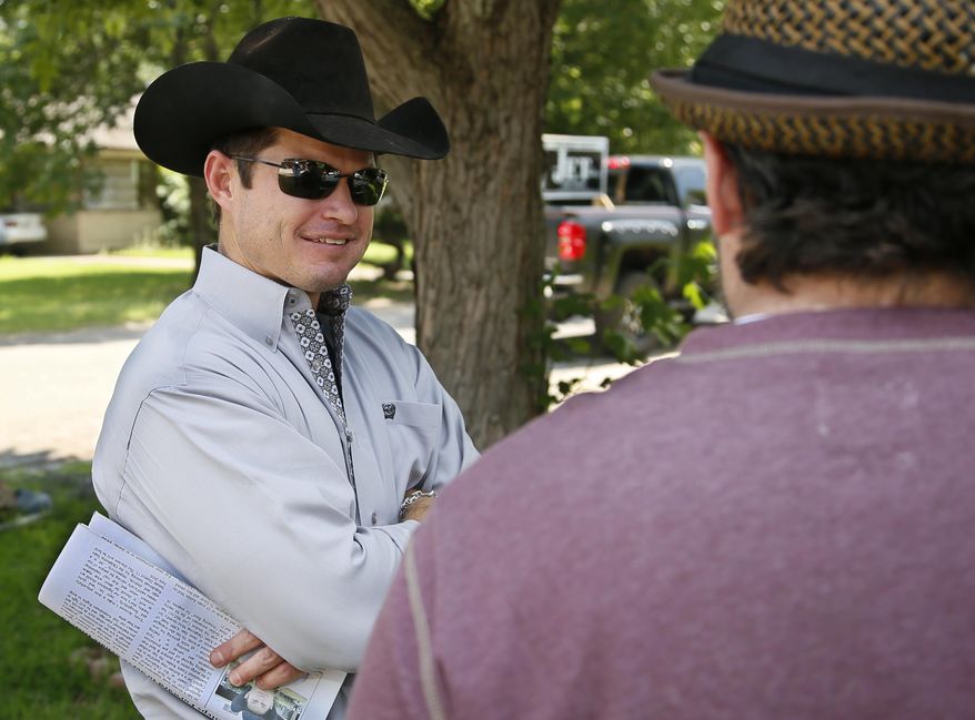 Jet McCoy, left, a Republican running for state Senate in the Ada area, talks to a voter as he knocks on door in neighborhoods in Ada, Okla., Thursday, June 9, 2016. Jet McCoy and his brother Cord McCoy are looking to capitalize on their fame as the Oklahoma cowboys-turned-reality-stars as both pursue seats in the state Legislature, one as a Republican and the other a Democrat. (AP Photo/Sue Ogrocki)