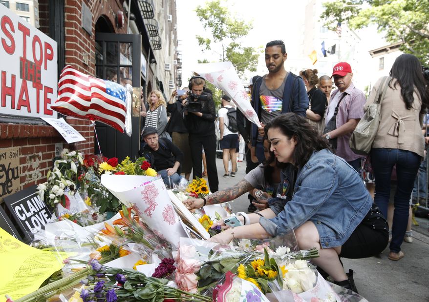 Giovanna Lopez, who says she knew several victims of the Orlando nightclub shootings, lays flowers for her friends at the historic Stonewall Inn, Monday, June 13, 2016, in New York. (AP Photo/Kathy Willens)
