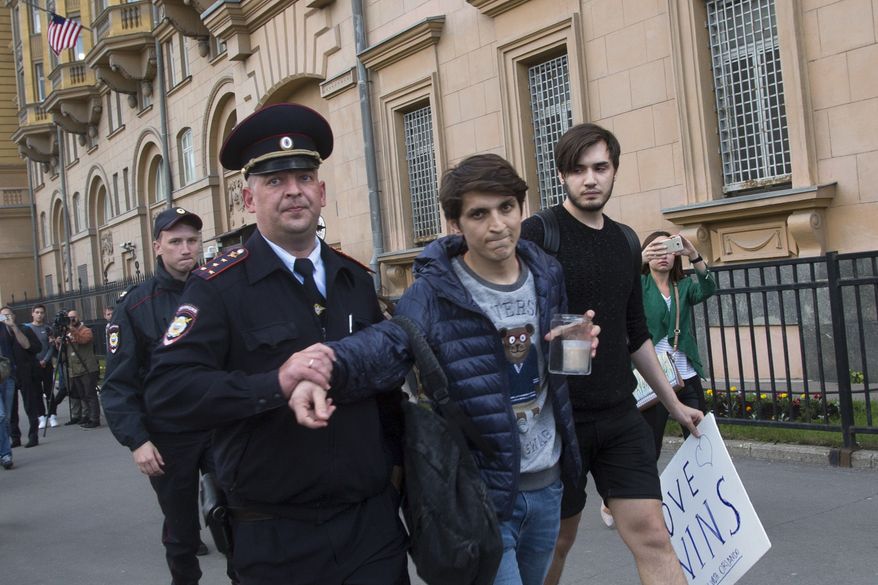 A Russian police officer detains a gay rights activist as he tries to show a poster reading "Love wins" at an impromptu memorial in memory of the victims of the Orlando nightclub attack at the U.S, Embassy in Moscow, Russia, Monday, June 13, 2016. (AP Photo/Alexander Zemlianichenko)