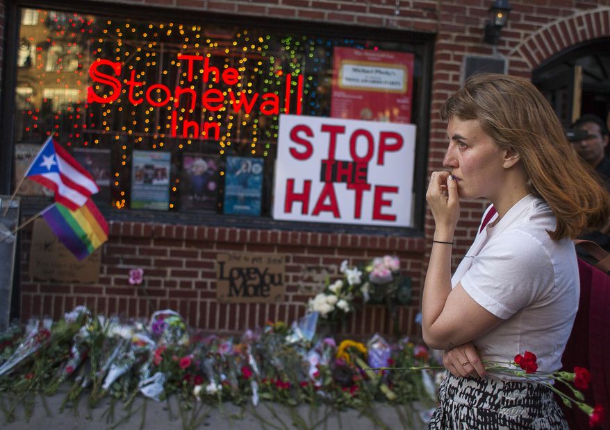 A woman cries and holds flowers in front of a makeshift memorial to remember the victims of a mass shooting in Orlando, Fla., in New York, Sunday, June 12, 2016. A gunman opened fire inside a crowded gay nightclub early Sunday before dying in a gunfight with SWAT officers. (AP Photo/Andres Kudacki)