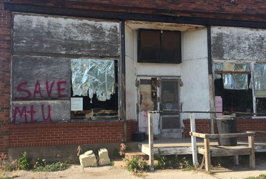 Darla Frakes, a Mount Union resident of 20 years, painted an appeal on the boarded-up window of the town’s former grocery store to stop the city from unincorporating. Last month, the City Council took the first step toward disincorporation by passing a resolution of intent to discontinue functioning as a city. The move came as the city of about 100 people struggles to pay the debt for a sewer system. (Julia Shumway/The Hawk Eye via AP)