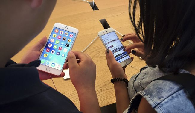 Customers try out Apple iPhone 6S models on display at an Apple Store in Beijing, Saturday, June 18, 2016. (AP Photo/Mark Schiefelbein) **FILE**