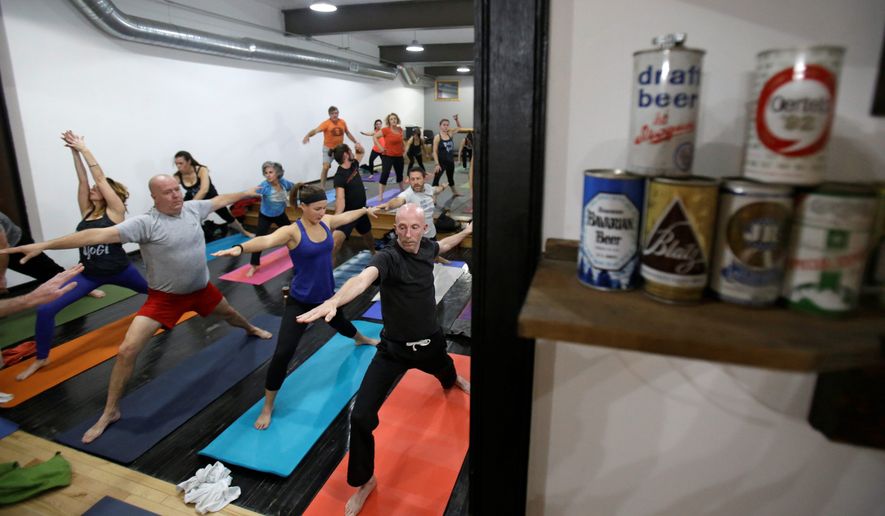 In this Thursday, Dec. 3, 2015, Greg Harris, right, practices yoga at the Platfrom Beer Co, in Cleveland. Craft breweries are partnering up with yoga studios around the country as more breweries are hosting classes to attract a new crowd to the bars and yoga studios are using the beer to get more men to try yoga. (AP Photo/Tony Dejak) **FILE**