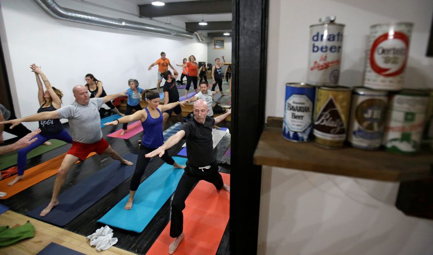 In this Thursday, Dec. 3, 2015, Greg Harris, right, practices yoga at the Platfrom Beer Co, in Cleveland. Craft breweries are partnering up with yoga studios around the country as more breweries are hosting classes to attract a new crowd to the bars and yoga studios are using the beer to get more men to try yoga. (AP Photo/Tony Dejak) **FILE**