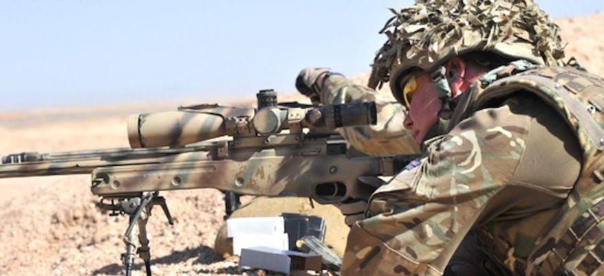 A British sniper looks through the scope of his L115A3 rifle. (British Army)