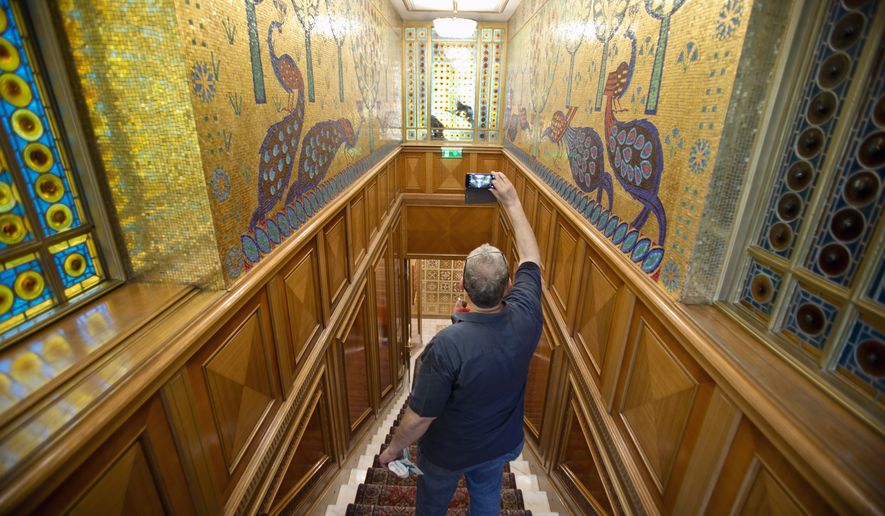 In this Saturday, June 11, 2016 picture a visitor takes pictures during a tour of Romanian communist dictator Nicolae Ceausescu's former family home, dubbed the Palace of Spring in Bucharest, Romania. More than 26 years after Nicolae and Elena Ceausescu were shot dead after a summary trial during the 1989 anti-communist revolt, fascination with the couple's opulent lifestyle remains, with thousands, Romanians and foreigners, visiting the Palace of Spring since it was transformed into a museum in March 2016.(AP Photo/Vadim Ghirda)