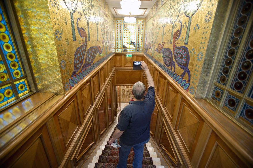 In this Saturday, June 11, 2016 picture a visitor takes pictures during a tour of Romanian communist dictator Nicolae Ceausescu's former family home, dubbed the Palace of Spring in Bucharest, Romania. More than 26 years after Nicolae and Elena Ceausescu were shot dead after a summary trial during the 1989 anti-communist revolt, fascination with the couple's opulent lifestyle remains, with thousands, Romanians and foreigners, visiting the Palace of Spring since it was transformed into a museum in March 2016.(AP Photo/Vadim Ghirda)
