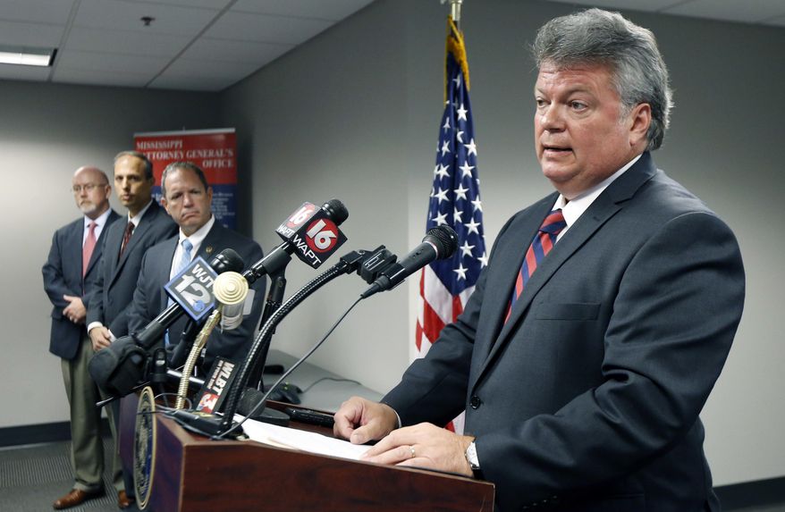 Federal agents, left, listen as Mississippi Attorney General Jim Hood tells reporters that the investigation into the infamous slayings of three civil rights workers in Mississippi is finally closed, 53 years almost to the day after the young men disappeared during "Freedom Summer," at a news conference Monday, June 20, 2016 in Jackson, Miss. The 1964 killings in Neshoba County sparked national outrage and helped spur passage of the 1964 Civil Rights Act. They later became the subject of the movie "Mississippi Burning." (AP Photo/Rogelio V. Solis)