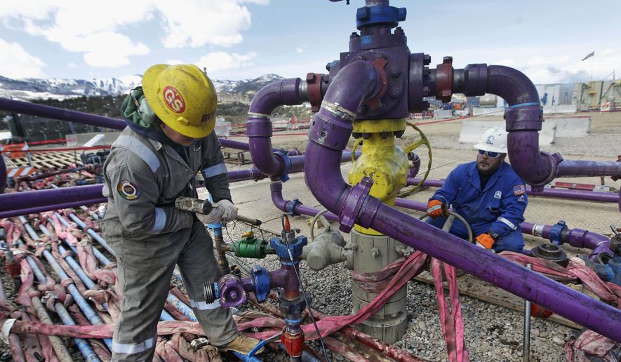 Workers tend to a well head during a hydraulic fracturing operation outside the town of Rifle in western Colorado, on March 29, 2013. (Associated Press) **FILE**