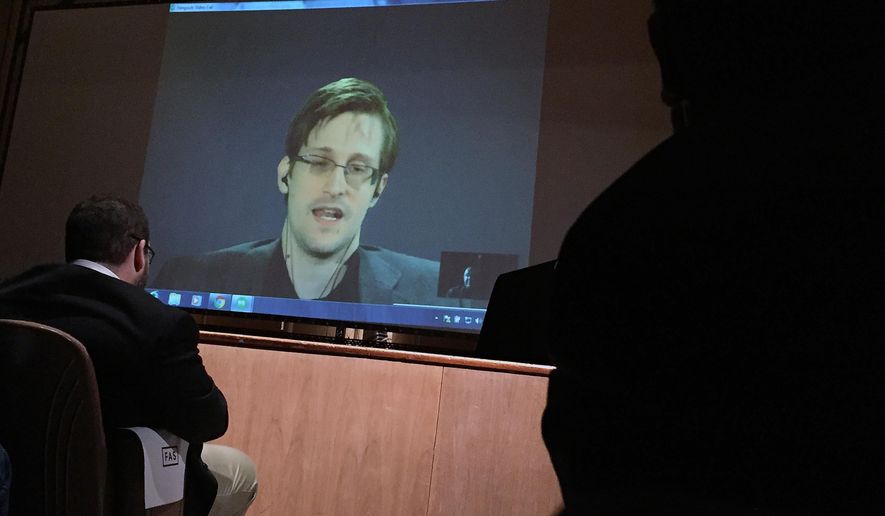 In this photo taken Feb. 17, 2016, former National Security Agency contractor Edward Snowden, center speaks via video conference to people in the Johns Hopkins University auditorium in Baltimore. (AP Photo/Juliet Linderman)