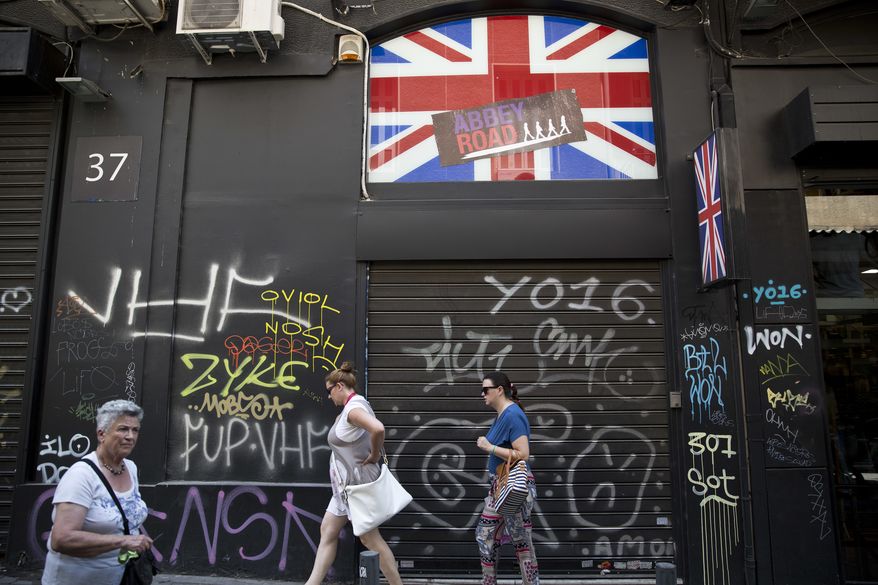 Women walk past a shuttered shop with a British flag in Athens, Friday, June. 24, 2016. Greece's prime minister says the British referendum dealt a severe blow to European unification, and should force a shift toward more democratic practices within the European Union.(AP Photo/Petros Giannakouris)