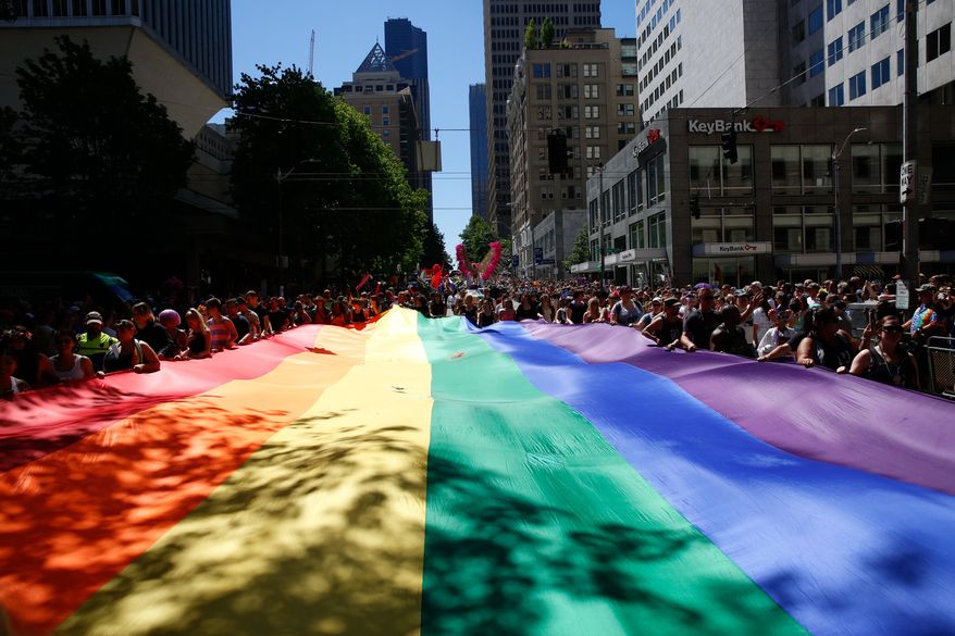 People help carry the rainbow flag during the the 42nd annual Seattle Pride Parade on Sunday, June 26, 2016. (Sophia Nahli Allison/The Seattle Times via AP) ** FILE **