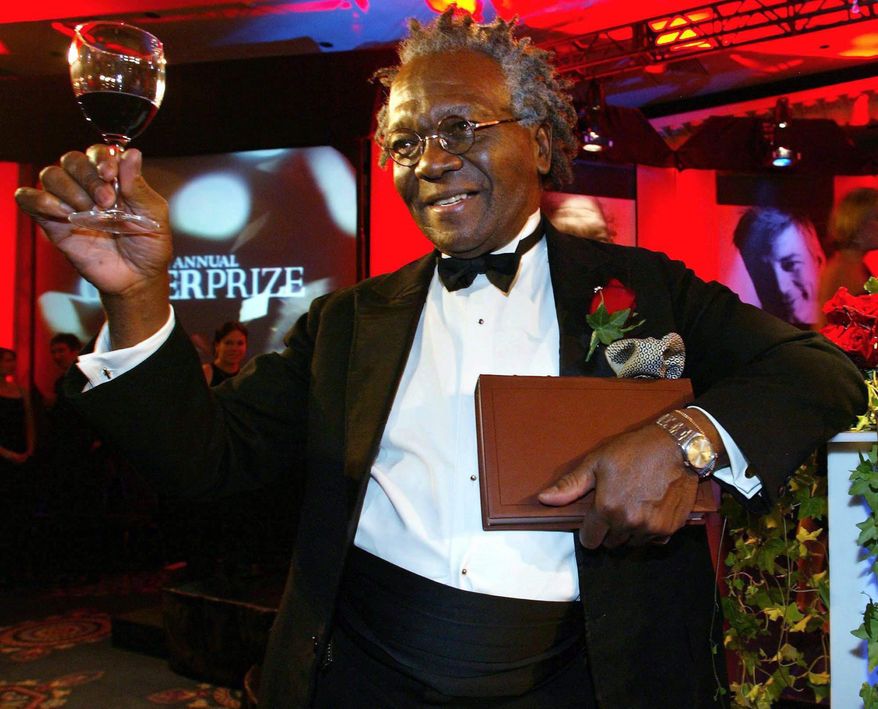In this Nov. 5, 2002 photo, Giller Prize winner Austin Clarke hoists a glass as he holds a copy of his book the Polished Hoe after winning the $25,000 literary prize at the Four Seasons Hotel in Toronto. Clarke, the award-winning Barbadian-born author who wrote about the immigrant experience and being black in Canada, has died at age 81. (Kevin Frayer/The Canadian Press via AP) MANDATORY CREDIT