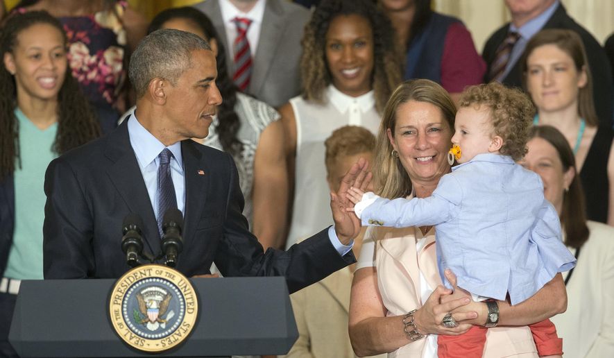 President Barack Obama, left, gets a high five from Oliver, son of Minnesota Lynx head coach Cheryl Reeve, right, in the East Room of the White House in Washington, Monday, June 27, 2016, during a ceremony where he honored the 2015 WNBA basketball Champion Minnesota Lynx. (AP Photo/Pablo Martinez Monsivais)