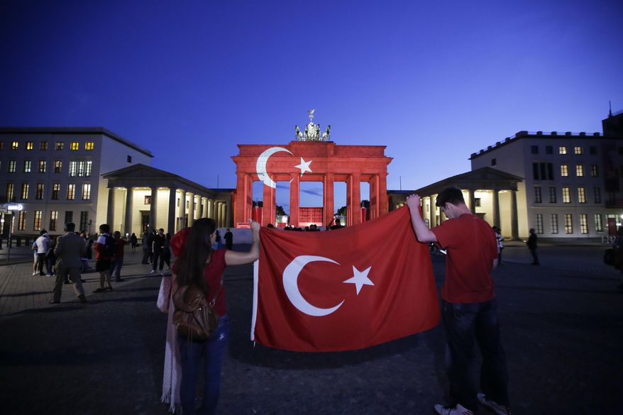 Two people hold a Turkish flag in front of the Brandenburg Gate in Berlin, Wednesday, June 29, 2016. The Brandenburg Gate was illuminated with Turkey's national flag after suicide attackers killed dozens and wounded more than 140 at Istanbul's busy Ataturk Airport late Tuesday, the latest in a series of bombings to strike Turkey in recent months. (AP Photo/Markus Schreiber)