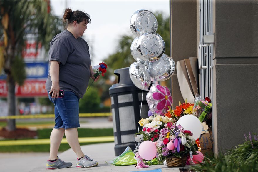 Penny Sevin, of Picayune, Miss., places a flower at a makeshift memorial outside the Raising Cane's franchise in Kenner, La., Thursday, June 30, 2016. Kenner police have arrested a second man, are questioning a third and are looking for a woman in the stabbing death of restaurant manager Taylor Friloux, 21, during an armed robbery. (AP Photo/Gerald Herbert)