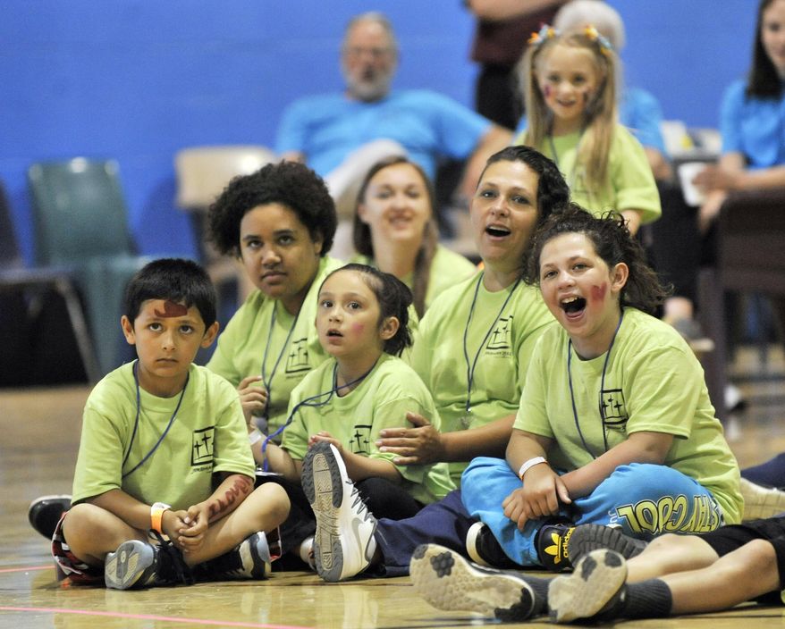FOR USE MONDAY, JULY 4, AND THEREAFTER- This photo taken June 4, 2016, shows Inmate Tara Vallejo of Lansing, second from right, sits with her children, from left, Giovanni Vallejo, 7, Destiny Coffman, 13, Serenity Vallejo, 6, and TaLeesa Coffman, 9, while they watch a strong man bend a horse shoe at the Women's Huron Valley Correctional Facility in Ypsilanti, Mich. Children get to spend a whole day with their mothers who are incarcerated in a program called One Day with God camp provided by Forgiven Ministry. (Robin Buckson/Detroit News via AP)