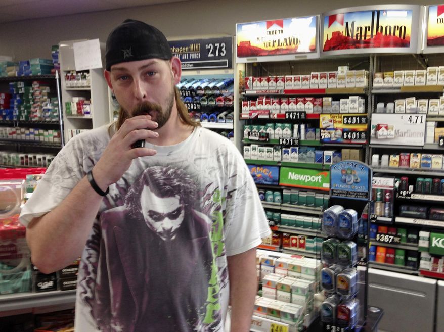 In this June 23, 2016 photo, Kenneth Houser takes a puff on an electronic cigarette at the We B Smokin store where he works in Jefferson City, Mo. Houser says he has smoked traditional cigarettes since age 13 but is trying to quit, partly because of the potential for prices to rise under a pair of tobacco tax initiatives proposed for the Missouri ballot. (AP Photo/David A. Lieb)