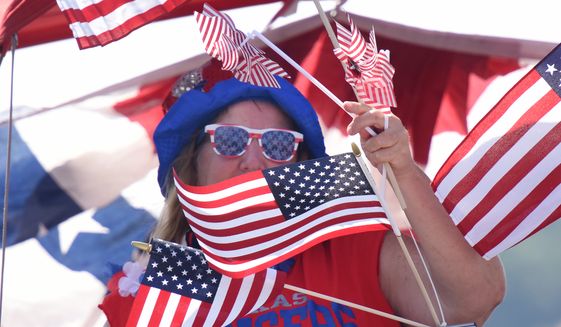 A woman is surrounded by American flags as she rides a boat at the Lake Cherokee Annual Boat Parade in Longview, Texas Saturday,  July 2, 2016. Participants in the event chose to decorate their boats in their a patriotic theme or open theme. Themed boats included the Olympics, super heroes, &quot;Duck Dynasty&quot; and Donald Trump.   (Sarah A. Miller/Tyler Morning Telegraph via AP)