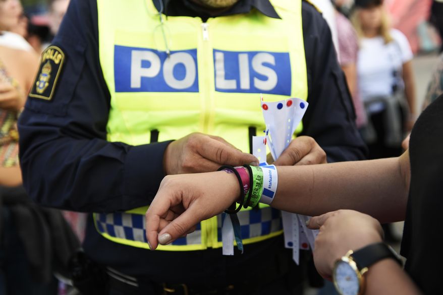 In this photo dated Friday July 1, 2016, A police officer attaches a bracelet with the text #tafsainte, meaning don’t grope, to a visitor's wrist at the Bravalla Festival in Norrkoping, Sweden, on Friday July 1, 2016. Swedish police told the media Tuesday July 5, 2016, that they are investigating five cases of alleged rape and more than a dozen suspected sexual assaults committed at the Bravalla Festival over last weekend. (Izabelle Nordfjell / TT via AP)