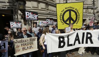 Protesters hold placards outside the Queen Elizabeth II Conference Centre in London, shortly before the publication of the Chilcot report into the Iraq war, Wednesday, July 6, 2016. (AP Photo/Matt Dunham)