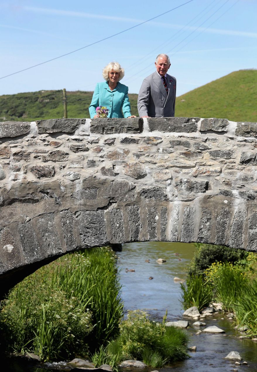 Prince Charles The Prince of Wales and the Duchess of Cornwall look out from a bridge in the village of Aberdaron, northern Wales, on the second day of their annual summer visit to Wales, Tuesday July 5, 2016. Wales soccer team face-off against Portugal on upcoming Wednesday during the Euro 2016 semi-final. (Chris Jackson / PA via AP)