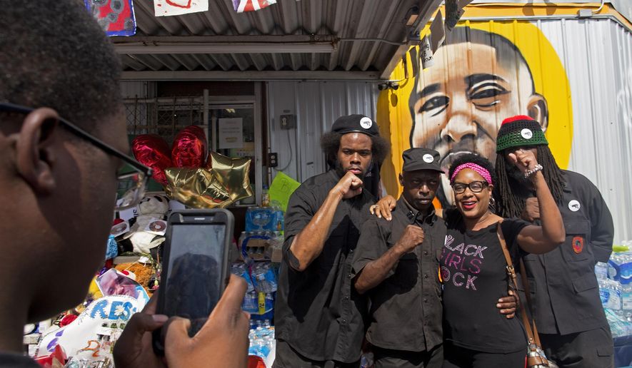 People pose for photographs with members of the New Black Panther party after they announced their intent to protest the death of Alton Sterling at the Baton Rouge Police Department Headquarters in Baton Rouge, Saturday, July 9, 2016. Protests were planned all over Baton Rouge by groups demanding justice for Alton Sterling, a black man killed by police. (AP Photo/Max Becherer)