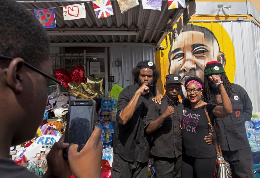 People pose for photographs with members of the New Black Panther party after they announced their intent to protest the death of Alton Sterling at the Baton Rouge Police Department Headquarters in Baton Rouge, Saturday, July 9, 2016. Protests were planned all over Baton Rouge by groups demanding justice for Alton Sterling, a black man killed by police. (AP Photo/Max Becherer)