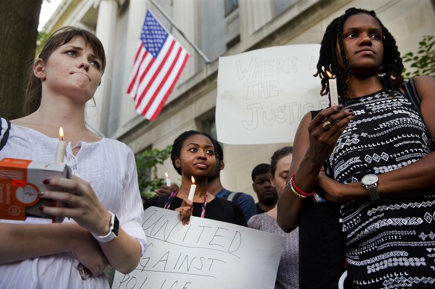 FILE - In this Friday, July 8, 2016 file photo, Ashley Wilson, 21, left, a student at George Washington University, Janay Richmond, and Jeanne Isler, right, both with the National Committee for Responsive Philanthropy, attend a rally in support of the "Black Lives Matter" movement in front of the Department of Justice in Washington. (AP Photo/Jacquelyn Martin)