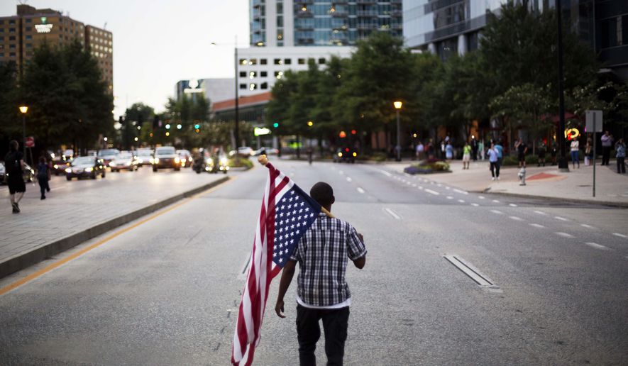 Skylar Barrett walks with an American flag in the middle of the street during a march through the Buckhead neighborhood against the recent police shootings of African-Americans on Monday, July 11, 2016, in Atlanta. (AP Photo/David Goldman)