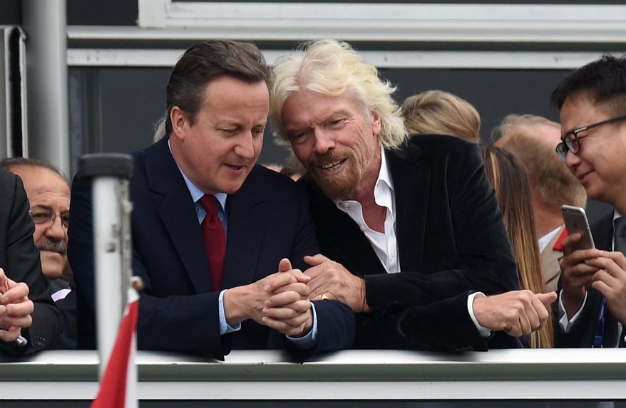 Britain's Prime Minister David Cameron, left, and Virgin boss Richard Branson talk at the Farnborough International Airshow in Farnorough, south England, Monday July 11, 2016. Britain has signed a contract for nine new P-8A Poseidon military aircraft, and Boeing announced Monday a planned expansion for its British operation, as the airshow attracts large international companies to announce their latest plans. (Andrew Matthews / PA via AP)