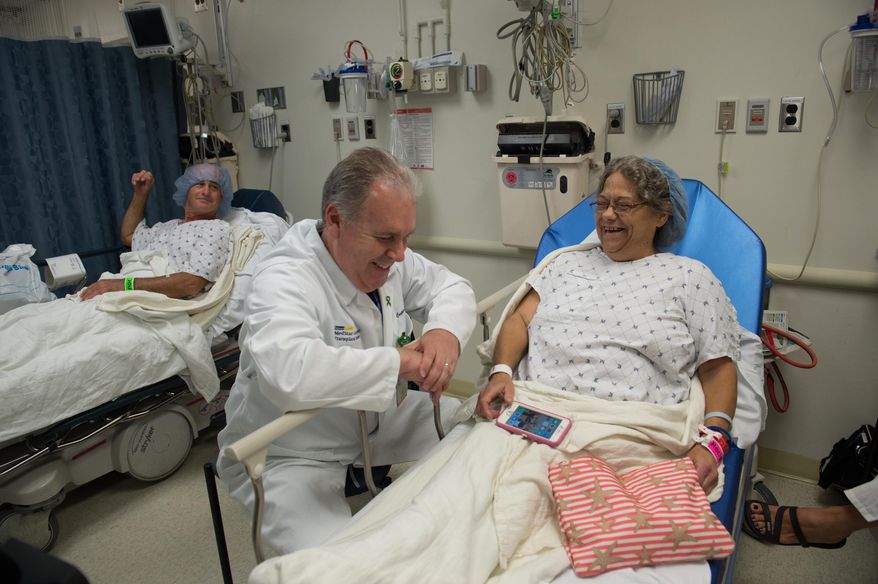 In this photo taken June 28, 2016, Brenda Hudson talks to surgeon Dr. Matthew Cooper as her husband and kidney donor Dana Hudson watches at left, prior to undergoing a kidney transplant at MedStar Georgetown University Hospital in Washington. Hudson's first kidney transplant lasted four decades, and her second showcases how far organ transplants have come and the hurdles that still await. More than 120,000 people are on the nation's waiting list for an organ transplant, most of them for kidneys, and thousands die before receiving one because of a dire shortage of donors. (AP Photo/Molly Riley)
