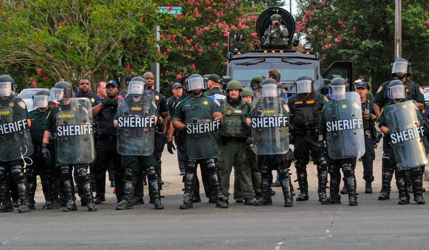 Police officers watch protesters gathering against another group of protesters in Baton Rouge, La., Sunday, July 10, 2016. Police officers responded to reports that protesters were en route to block Interstate 10 and prevent another group of protesters from marching. (Scott Clause/The Daily Advertiser via AP)