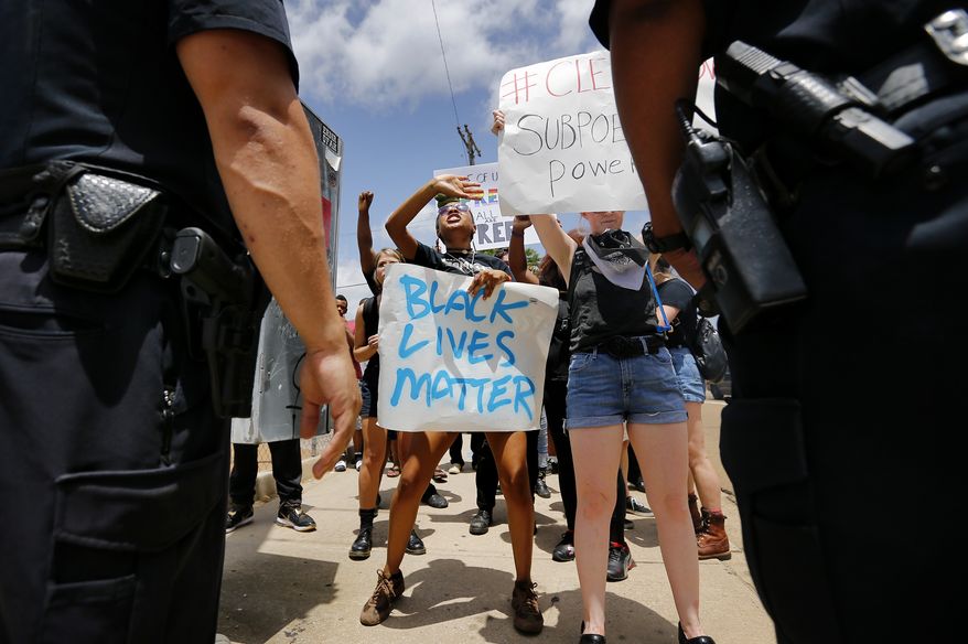 Protesters with the Black Lives Matter movement  argue with police to let them walk down the sidewalk during a rally outside Graceland on Elvis Presley Blvd Tuesday afternoon, July 12, 2016 in Memphis, Tenn.  Dozens of protesters associated with the Black Lives Matter movement demonstrated Tuesday outside the gates of Graceland, the former home of Elvis Presley. Police said four people were detained for blocking the street.  (Mike Brown/The Commercial Appeal via AP)