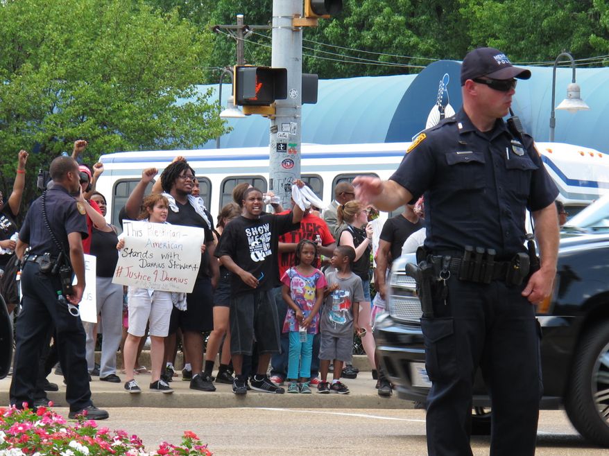 A police officer controls traffic as Black Lives Matter protesters wait to cross the street in front of Graceland, the former home of Elvis Presley, on Tuesday, July 12, 2016, in Memphis, Tenn. (AP Photo/Adrian Sainz).