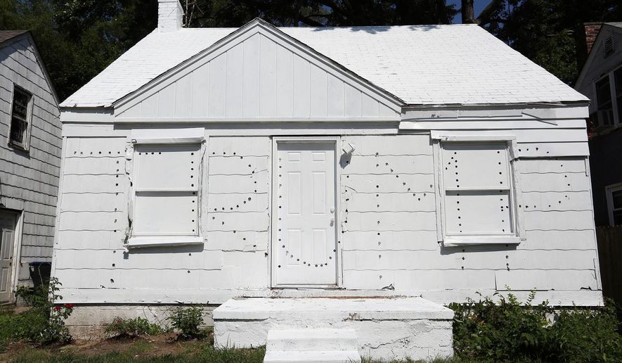 This photo taken July 12, 2016, shows a new project by Ryan Mendoza, an artist previously known for using an abandoned Detroit home for art, who has built a new project using two abandoned homes on either side of an occupied home. The artist has taken the homes that sit empty and has painted them white and then punched holes in the homes to spell Trump on one and Clinton on the other. At night the lights that he installed into the holes illuminate and the message he wants to convey is that there is a lack of political choice with Clinton and Trump. In addition, this signifies the state of America in the middle of this political campaign. (Regina H. Boone/Detroit Free Press via AP)