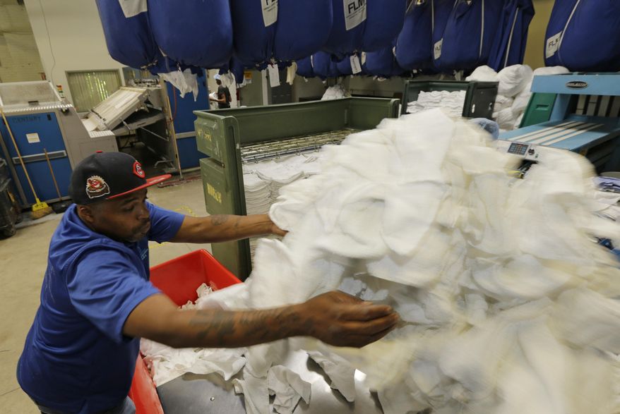 In a Friday, June 24, 2016 photo, Chris Brown moves laundry at the Evergreen Cooperative Laundry in Cleveland. Donald Trump's effort to unite a splintered Republican Party around his candidacy is about to take center stage in a city that is itself deeply fractured. Brown, a lifelong Clevelander, admits he was part of the problem in his younger days. Caught selling drugs, he went to prison for three years. Afterward, getting by was a struggle until he started working at the commercial laundry four years ago. (AP Photo/Tony Dejak)