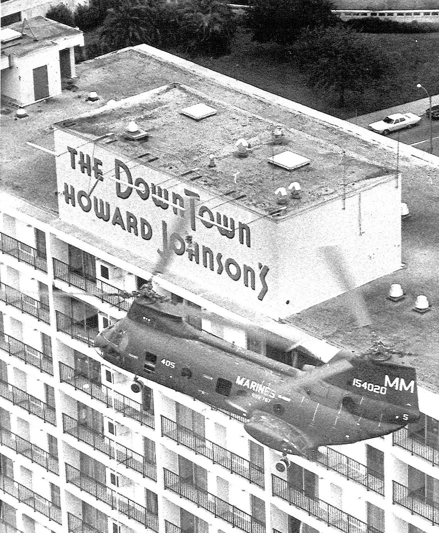 FILE - In this Jan. 8, 1973 file photo, a Marine Corps helicopter makes a pass over the Downtown Howard Johnson Motor Lodge in New Orleans firing at the block house at center where police believe sniper Mark Essex was hiding. Marine Corps Lt. Col. Chuck Pitman piloted the aircraft that carried NOPD Sgt. Antoine Saacks and the NOPD officers that shot Essex. The July 7, 2016 sniper attack in Dallas was gloomily reminiscent of the 1973 shooting spree in downtown New Orleans. The attacker was Mark Essex, a black former military man , who was shot and killed from a helicopter. He harbored deep-seated hatred for whites that people who knew him said took root in the Navy. (AP Photo, File)